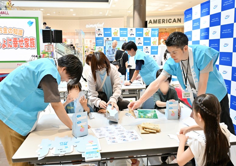福岡銀行のブースでATM貯金箱を作る子供とそれをサポートする銀行職員の様子