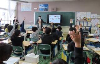 財政に関するクイズを出す講師と挙手する児童