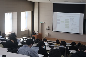 講義室でスクリーンに映し出した資料を見ながら講演を聞く学生たちの様子