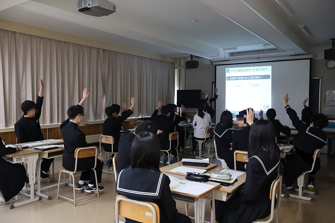 スクリーンを見ながら手を挙げて質問に答える生徒達（穂別中学校）