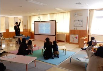 お金について話をする講師と、参加する親子の様子