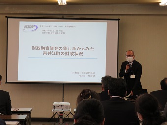 奈井江町財政研修会でスクリーンに資料を写して奈井江町の財政状況について説明（講演）をしている職員とそれを聞く参加者