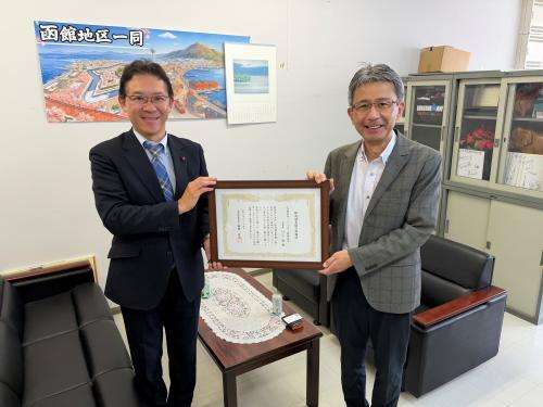 贈呈後に感謝状を掲げる本部長と所長
