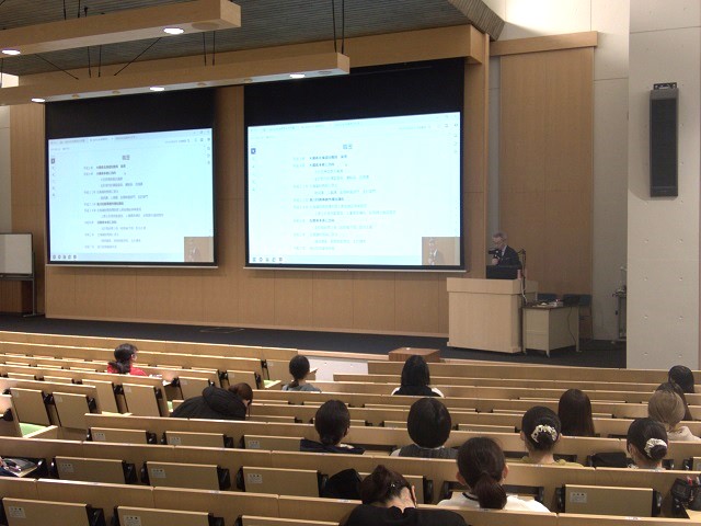 名寄市立大学の講義室で、学生がスクリーンに映された資料を見ながら講演を聞いている様子