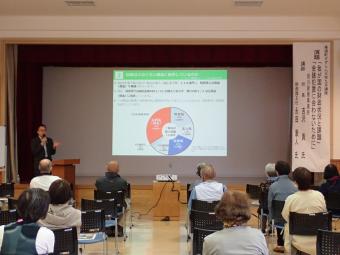 日本の財政について説明する講師と説明を聞く受講者