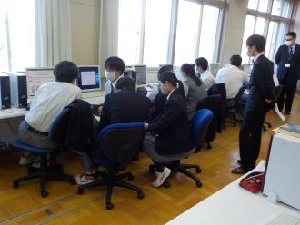 パソコン画面を見ながらグループで議論する生徒と見守る講師