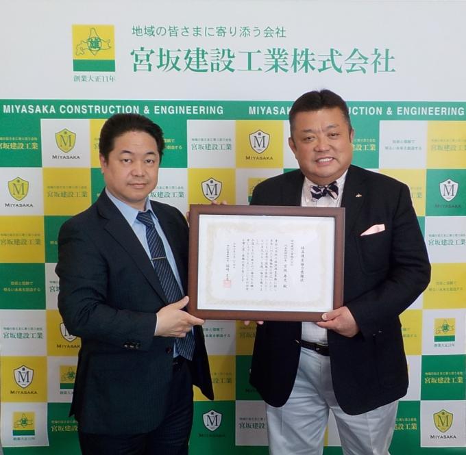 表彰状を掲げる帯広財務事務所長と宮坂建設工業社長
