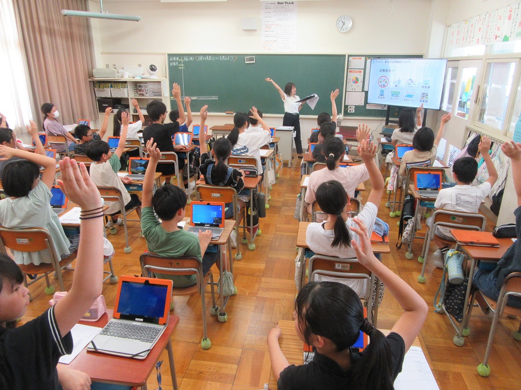 クイズに参加して手を挙げる児童