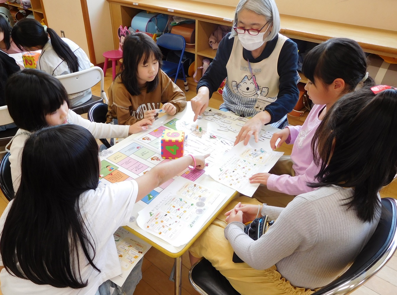 5人の生徒がすごろく盤を囲っておつかいを体験するすごろくをしている様子