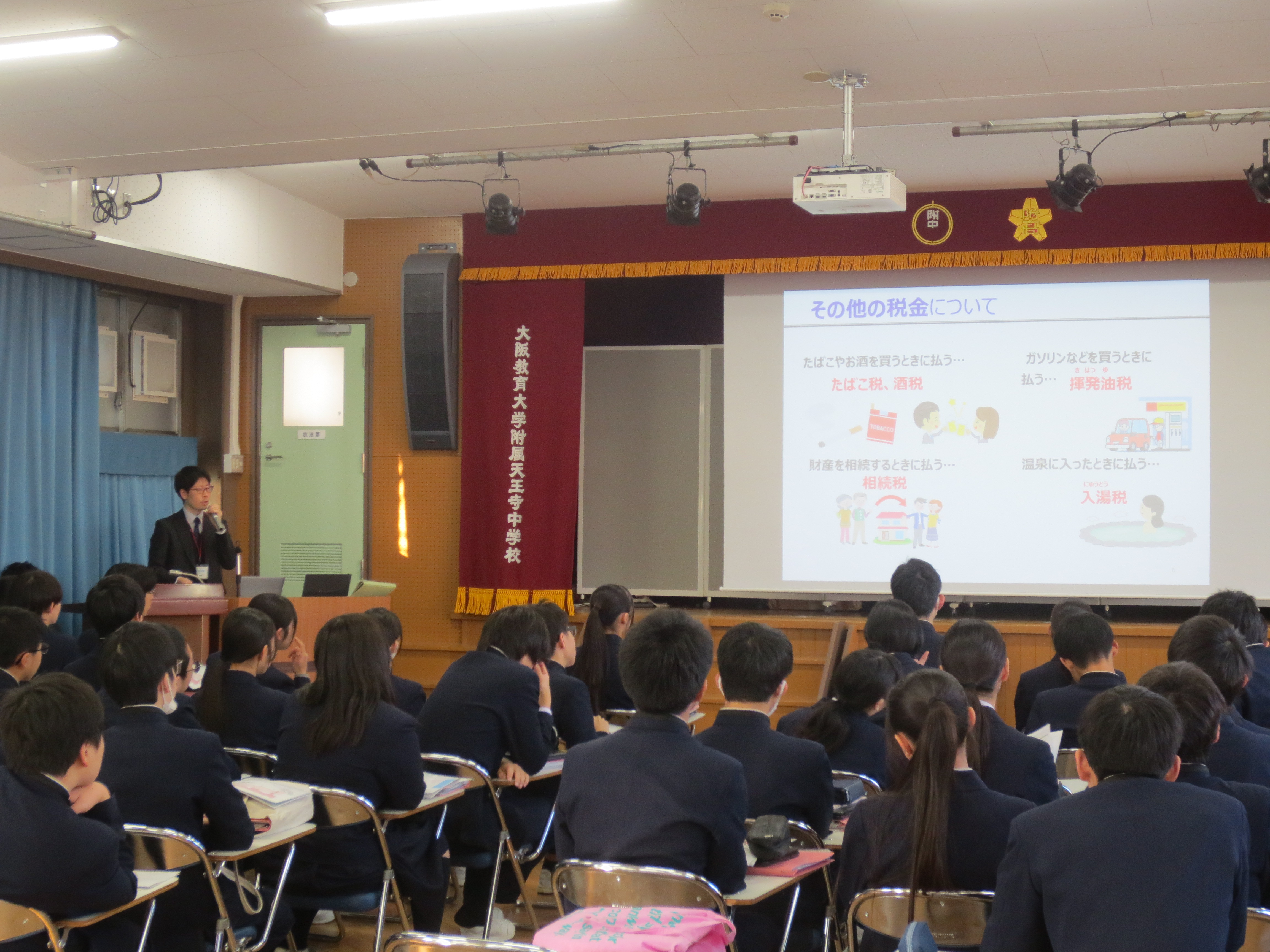 財政教育プログラムで講師がクイズを交えて講義をしている