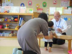 秋田財務事務所職員がお金のはなしをしているところにお子さんが近づいてきた様子