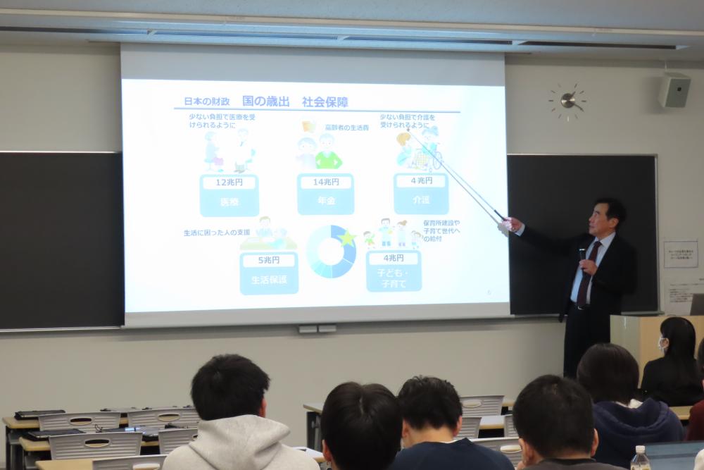 職員が学生にスライドを用いて説明している様子