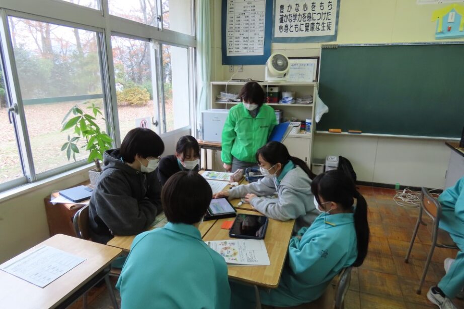 グループになって話し合う生徒に、財務局職員がアドバイスしている様子