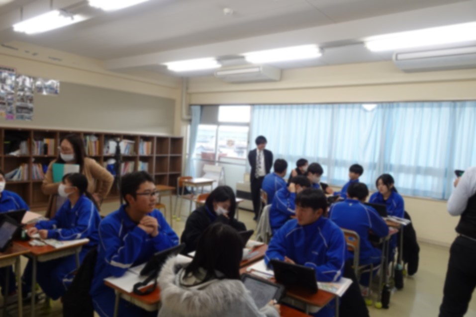 グループになって話し合う生徒たちに財務局職員がアドバイスしている様子