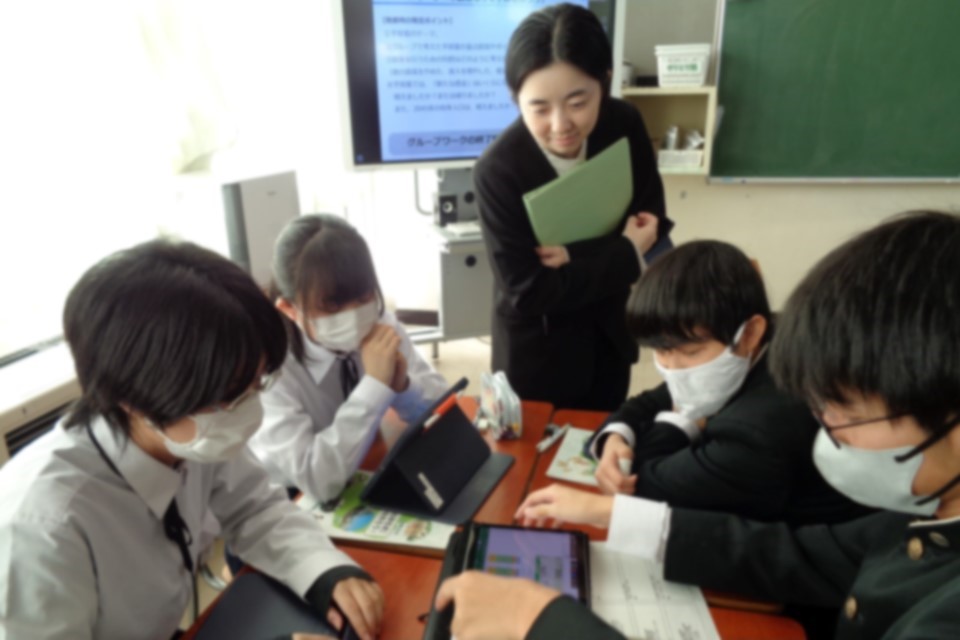 グループになって話し合う生徒に、財務局職員がアドバイスしている様子