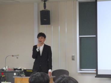 前方に立った講師が、スクリーンの横で説明している様子
