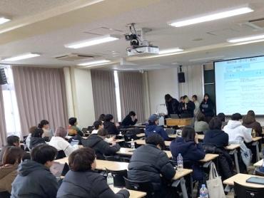 複数の受講者が前方に集まり、スクリーンを使って発表している様子