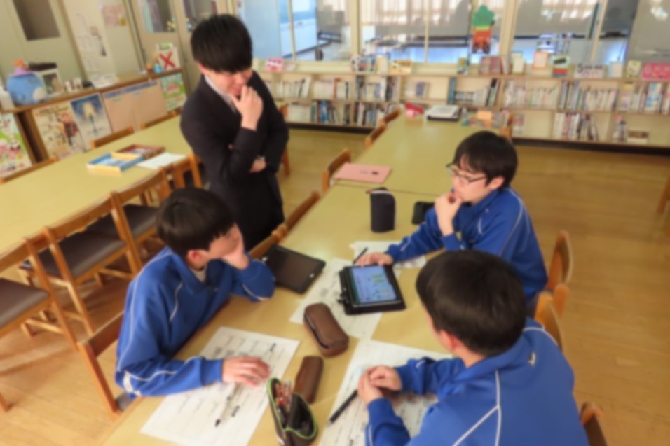 グループになって予算案を話し合う生徒たちに財務局職員がアドバイスをしている様子