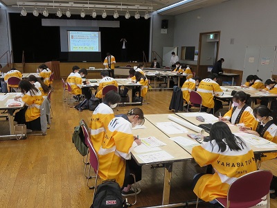 4,5人ずつのグループに分かれ、黄色い法被を着て未来人になりきり、グループワークに取り組む学生たち