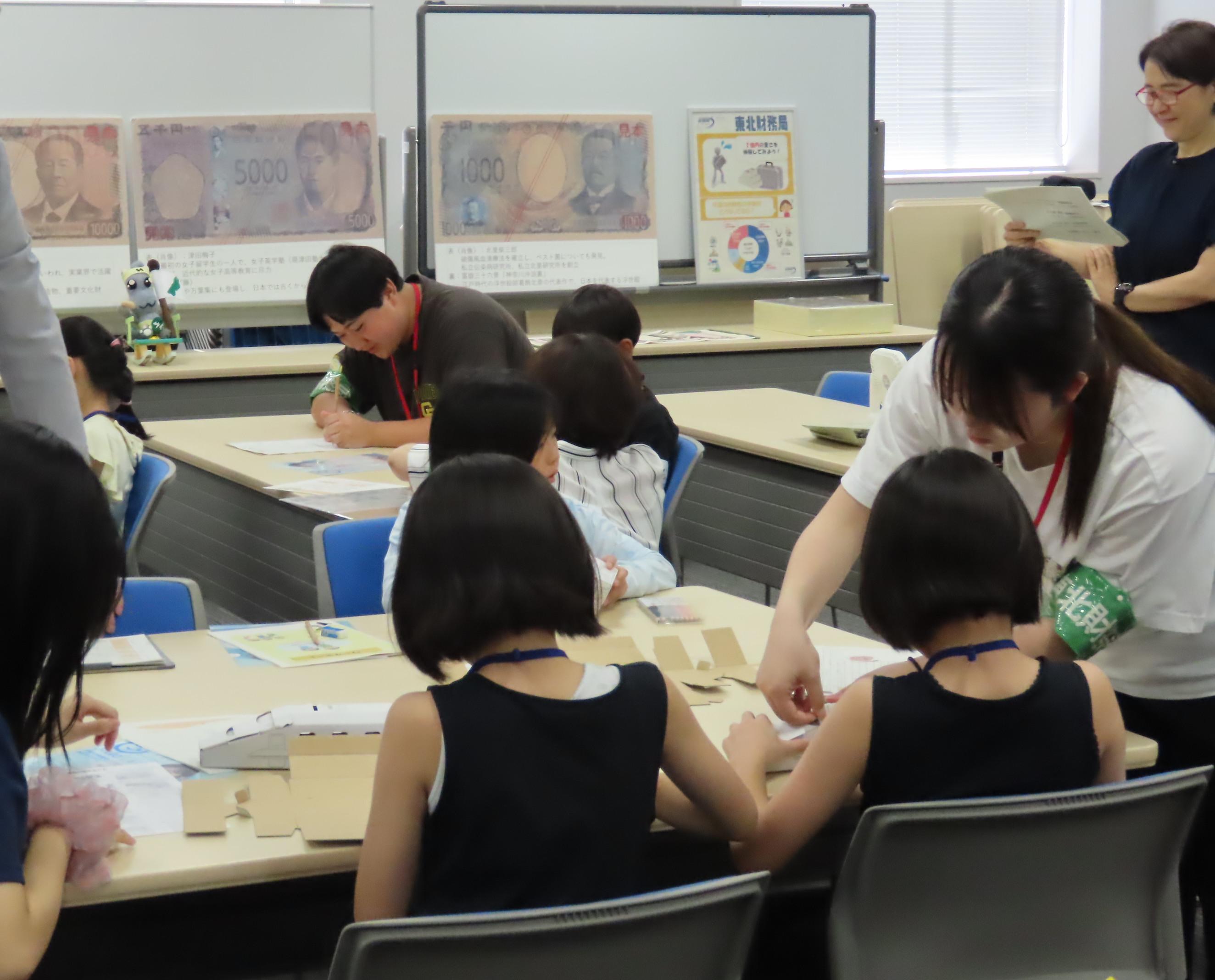貯金箱作りに挑戦する子供たちとサポートする東北学院大学の学生の様子
