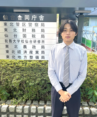 庁舎前に立つ管財部統括国有財産管理官（３）所属の若手職員