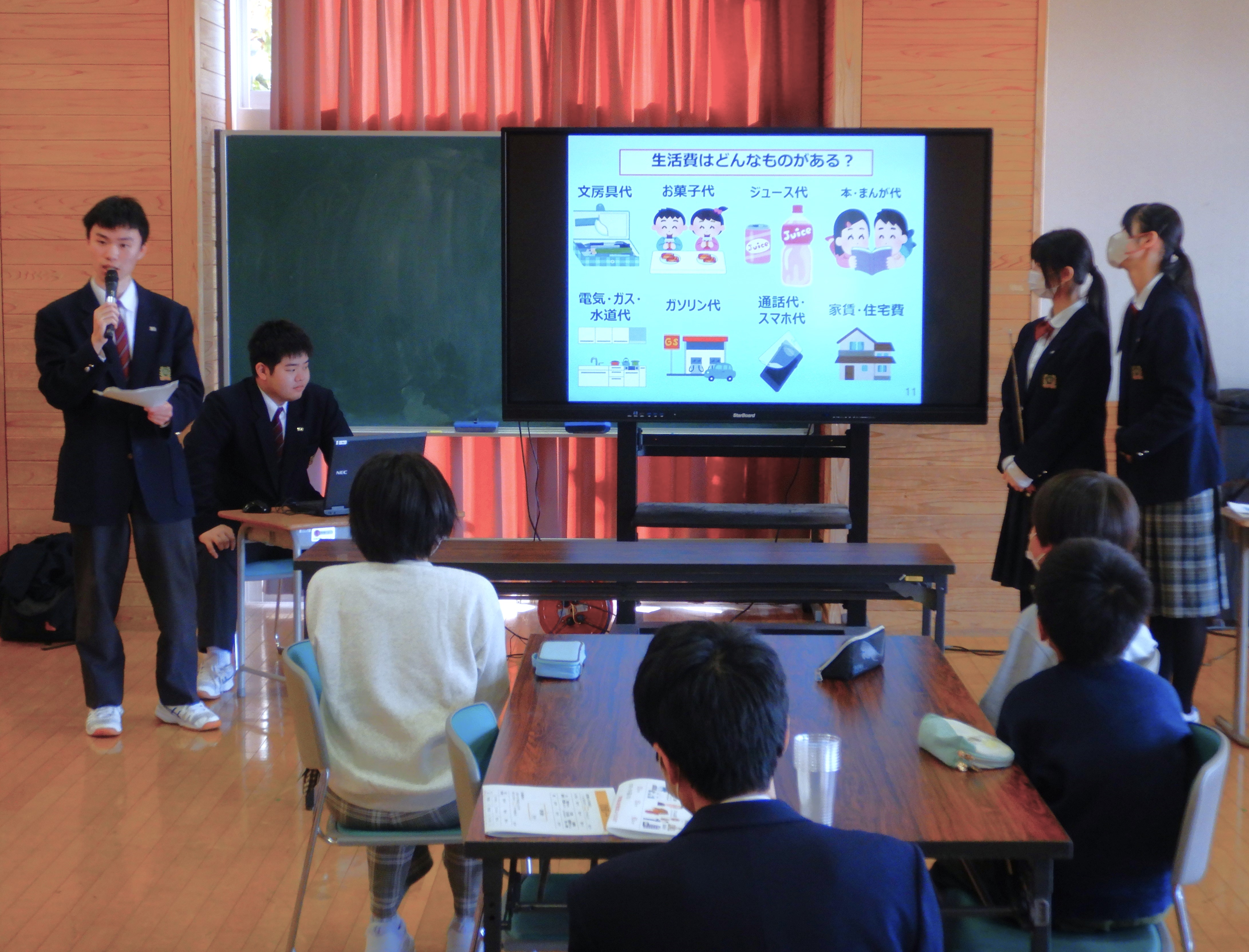 資料をモニターに投影し、説明する高校生と聞き入る小学生