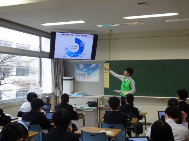 財務事務所職員が教室のモニターに投影したスライドを使用し財政の説明を行っている様子