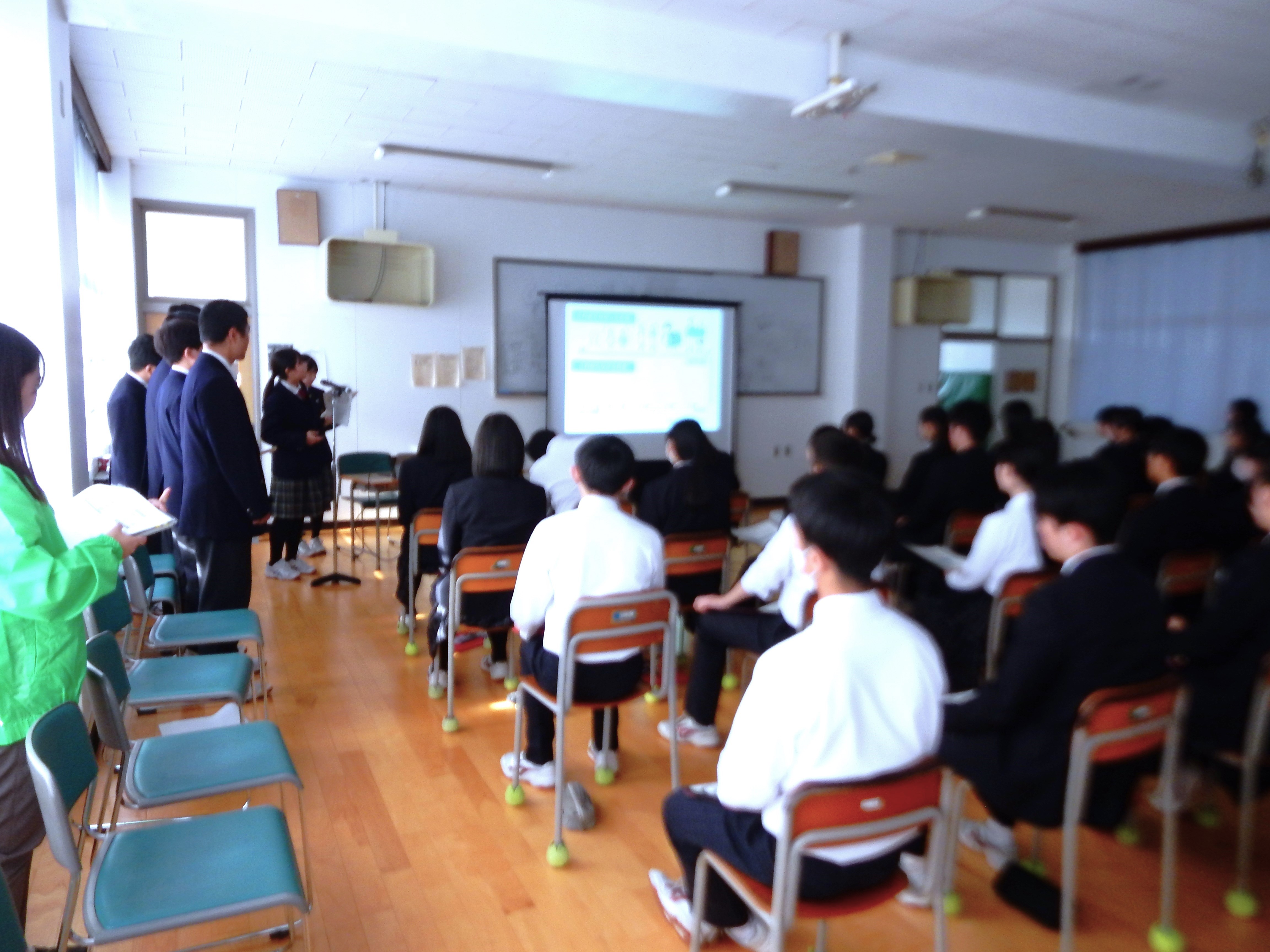 投影されたスライドを見ながら講義を受ける中学生